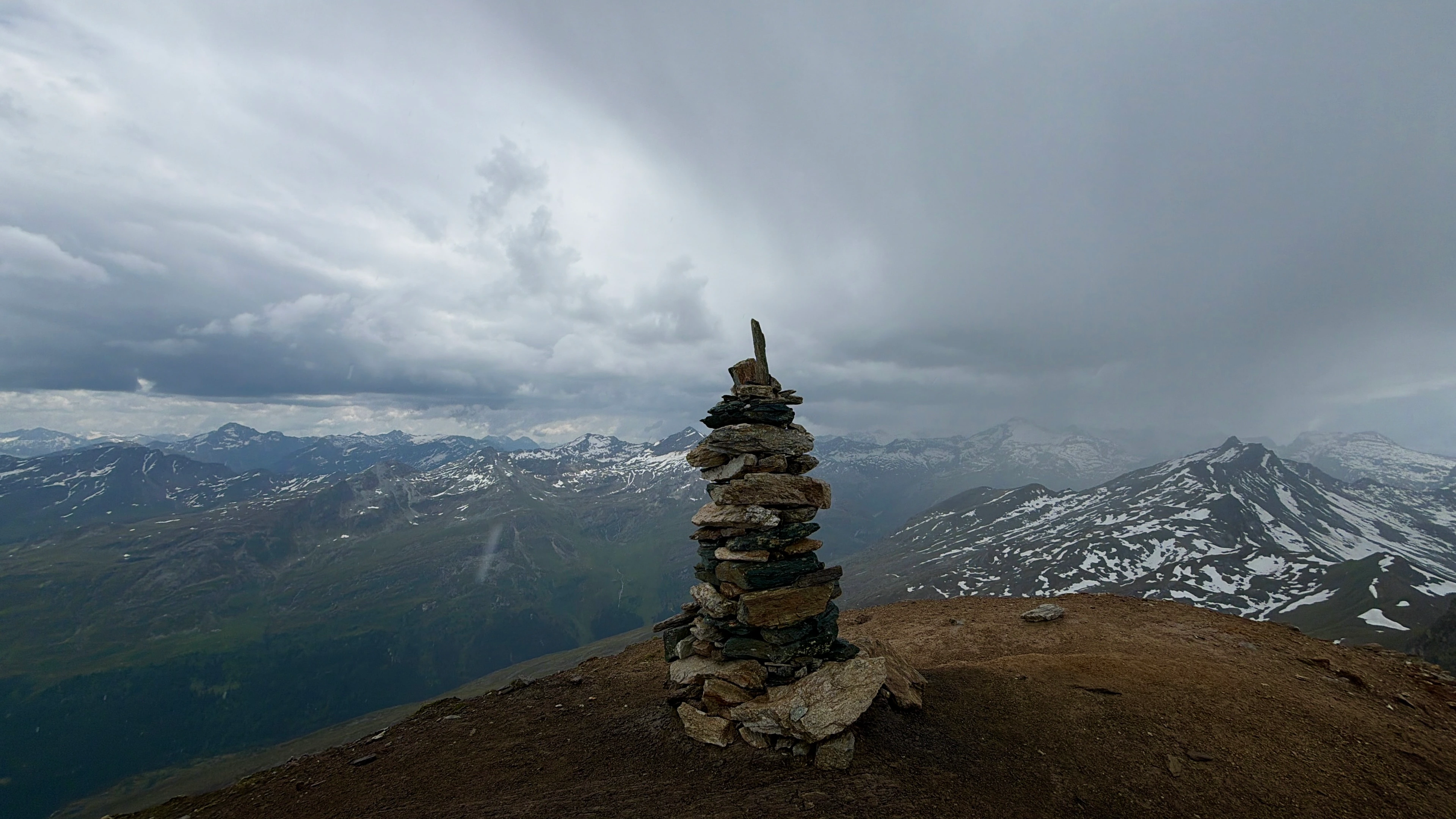 A solitary hand-stacked cairn centered on a misty Alpine ridge.
